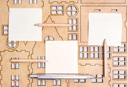 Plywood home model kit with paper notes, pen and pencils. House design and building project background.の写真素材
