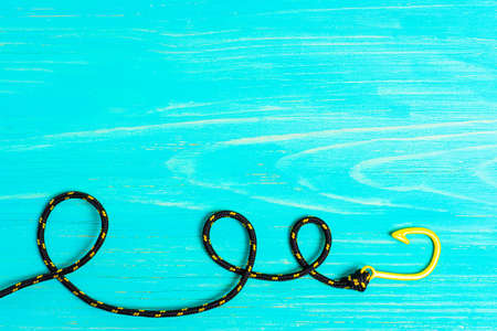 Black and yellow fishhook bracelet on a blue wooden background with copy space.の写真素材