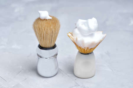 Comparing a new shaving brush with a worn one. Saving through spending.の写真素材