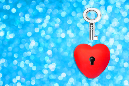 Dreamy blue bokeh background with a heart shape having a keyhole and a silver-toned skeleton key....