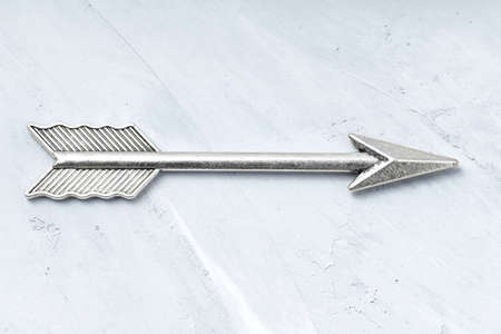 Close-up of an antique silver feathered arrow isolated on a concrete background.の写真素材