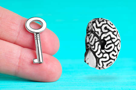 Floating human brain and master key in hand isolated on blue background. Unlock full power of the brain.の写真素材