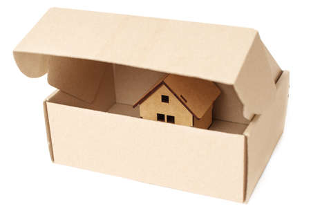 Partly opened cardboard shipping box with a tiny new wooden house inside. Real estate sale concept.の写真素材