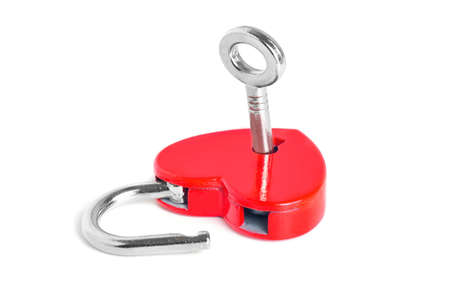 Silver-toned key in a small open red heart-shaped padlock isolated on white background. Symbolic...
