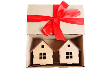Two wooden toy house models in a small cardboard box having a red ribbon bow on the cover. Creative real estate offer concept.の写真素材
