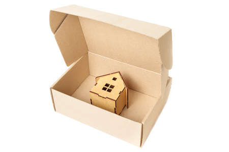 Wooden toy house in a shipping box isolated on white. Home relocation concept.の写真素材