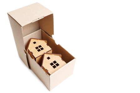 Two wooden toy houses inside a small shipping box. Creative moving in concept.の写真素材
