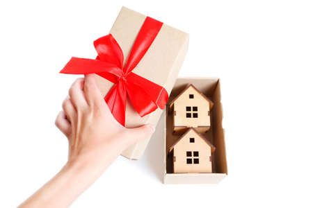 Opening a gift box having toy wooden house models inside. Duplex property investment concept.の写真素材