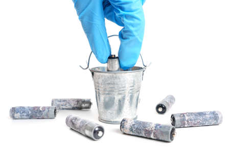 Used batteries recycling concept. Hand collects dead batteries in a bucket.の写真素材