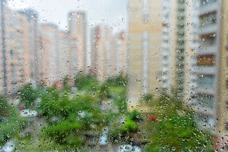 Raindrops on the window with a defocused cityscape on a summer day