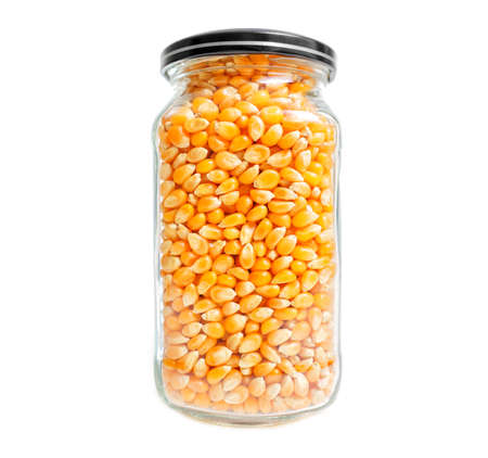 Small jar full of yellow popcorn kernels isolated on white backgroundの写真素材
