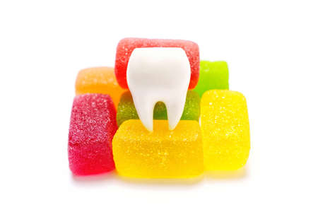 Large tooth model with a bunch of colorful jelly candies isolated on white background. Sugar affecting dental health.の写真素材
