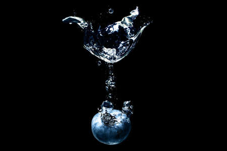 Fresh blueberry dropped into water with splashes against black backgroundの写真素材