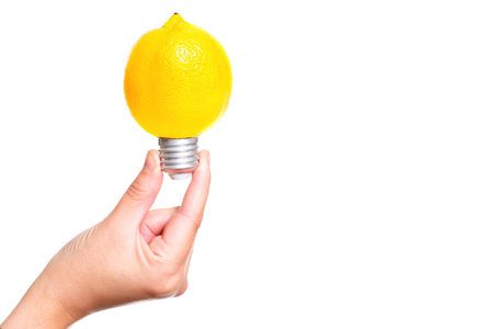 Light bulb made from a fresh lemon in hand isolated on white background.の写真素材