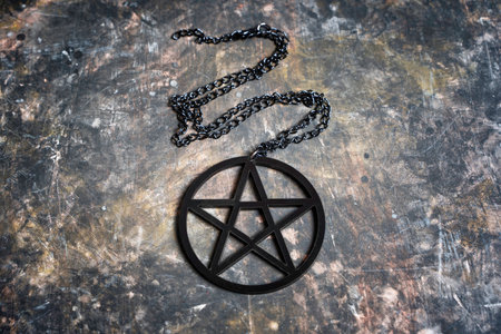 Close-up of a large black pentagram pendant placed on dark grungy backgroundの写真素材