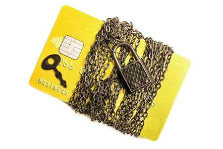 Credit card wrapped with chain and secured with a massive padlock and a key isolated on white...