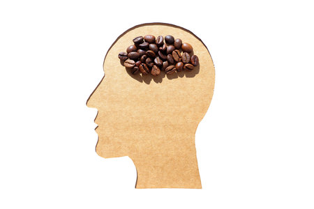 Male head profile shape paper cut-out with roasted beans imitating the brain. Creative coffee...