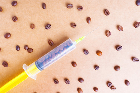 Roasted coffee beans and medical syringe background. Creative caffeine addiction concept.の写真素材