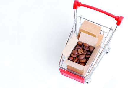 Open box of fresh roasted coffee beans in a miniature push trolley isolated on a neutral background with copy space.の写真素材