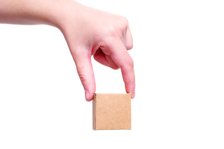 Close-up of a hand pinch holding a miniature shipping box isolated on white backgroundの写真素材