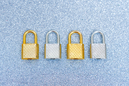 Row of four steel padlocks on a glittering background.の写真素材