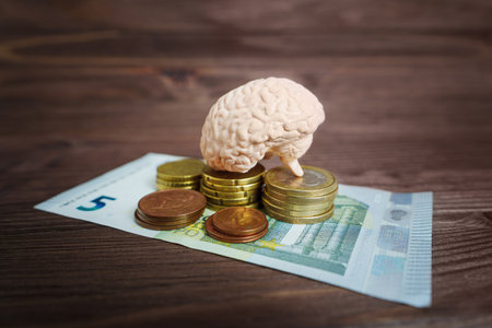 Small human brain placed on euro coins stacks on a wooden table. Creative financial wisdom concept.の写真素材