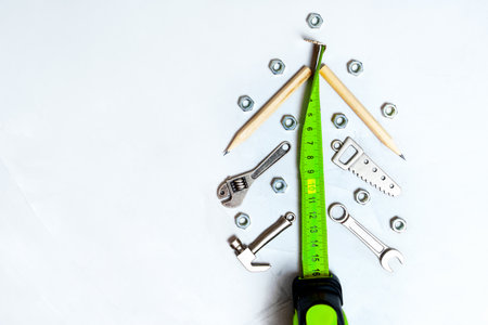 Roll meter and miniature copies of essential hand tools arranged into a New Year tree shape on a concrete background. Christmas holidays construction industry shut down concept.の写真素材