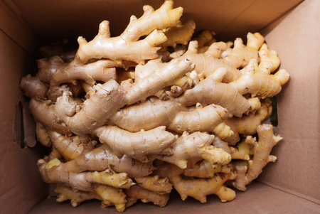 Cardboard box filled with fresh ginger roots, as seen from a top-down perspective. Food or...