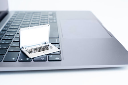 Miniature toy laptop placed on a top of the keyboard of a full-sized laptop. Creative working on the go concept.の写真素材