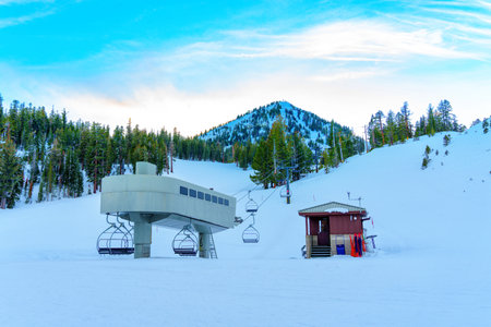 Lift station at a ski resort, with stunning views of snow-covered slopes, majestic mountains, and a beautiful pine forest in the background.の写真素材