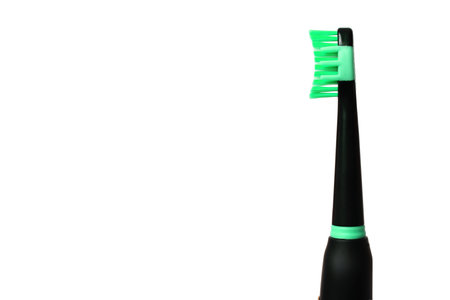Close-up view of a black electric toothbrush with green elements and soft green bristles isolated on white background with copy space.の写真素材