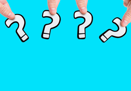 Group of white question marks shapes in hands isolated on blue background with copy space. Creative...