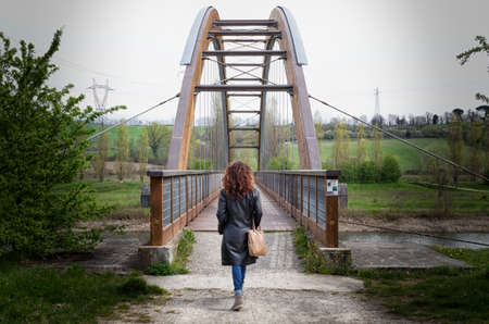 woman back as shes about to cross a bridgeの写真素材
