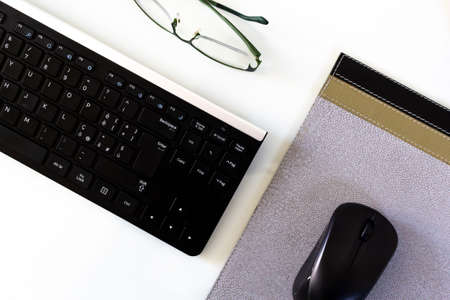 empty workstation with keyboard, mouse, pad and glasses
