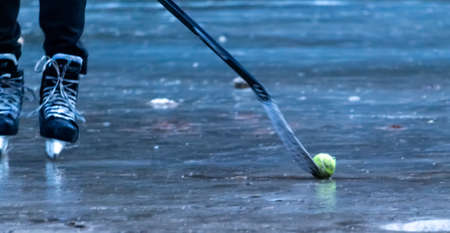 hokey player on the frozen lake hitting the ball with the batの写真素材