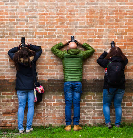 three photographers shooting upwards leaning against the wallの写真素材