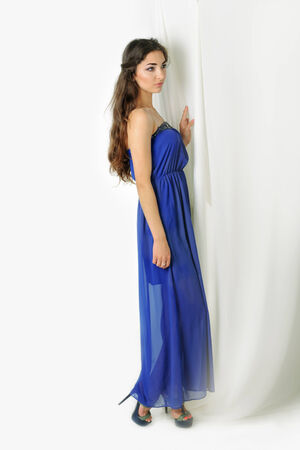 Girl in blue dress near curtains posing in studioの写真素材