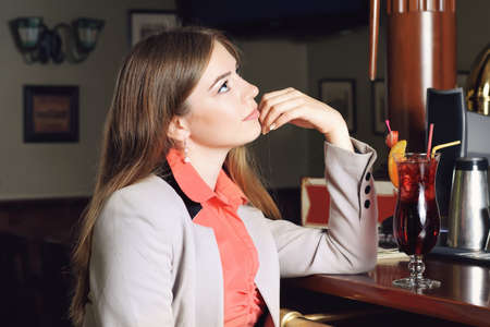 Girl in the bar expects order. Girl sitting at the barの写真素材