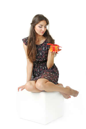 Beautiful girl sitting on the cube and holding a giftの写真素材