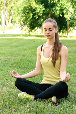 A beautiful girl performs exercises of yoga in the Parkの写真素材