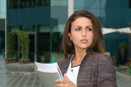 Business woman with a folder in her hands strongly indignant against the backdrop of the cityの写真素材