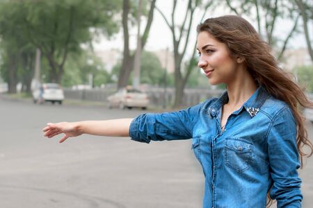 Beautiful young woman hitch-hiking in sityの写真素材