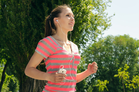 Girl while running listening to music through headphones outdoorsの写真素材