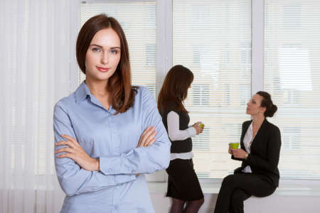 Girl in formal attire is standing in the foreground, and her colleagues have a talking in the backgroundの写真素材