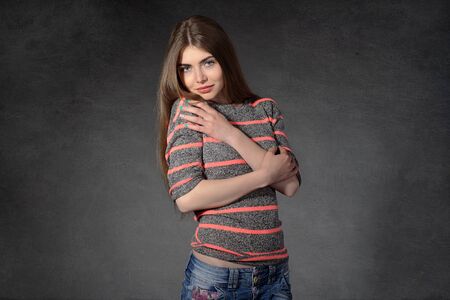 Concept human emotions. Woman shows modesty or shyness against a dark backgroundの写真素材