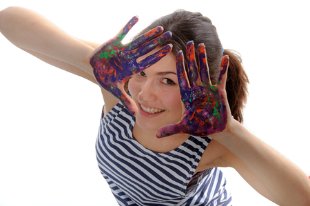 Woman looks out her hands painted in colorful paint and she smiles against an isolated background and top viewの写真素材