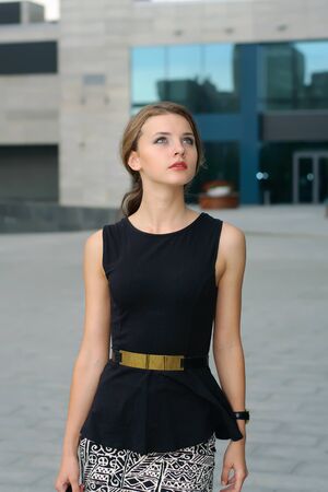 Business woman in formal clothes is on the city's business district and is looking upの写真素材