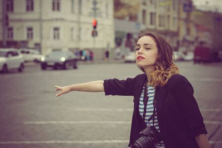 Vintage photo. Woman with the camera catches the car on the road in the cityの写真素材