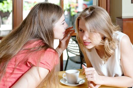 One girl whispers in the ear of another a secretの写真素材