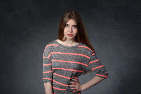 Indignation, menacing concept. Woman standing with hands on hips against a dark gray backgroundの写真素材